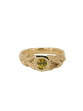 Load image into Gallery viewer, A yellow gold ring with a round natural diamond and hand-carved leaf detailing on a plain background.