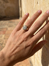 Load image into Gallery viewer, Hand wearing a diamond ring against a stone wall.